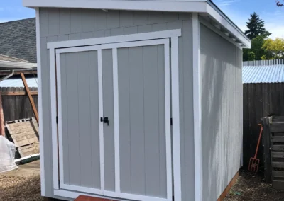 Picture of a light gray shed with white trim and a ramp leading to the entry door